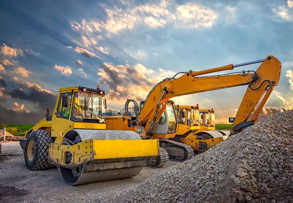 parked drum roller and excavators at the construction site, afte