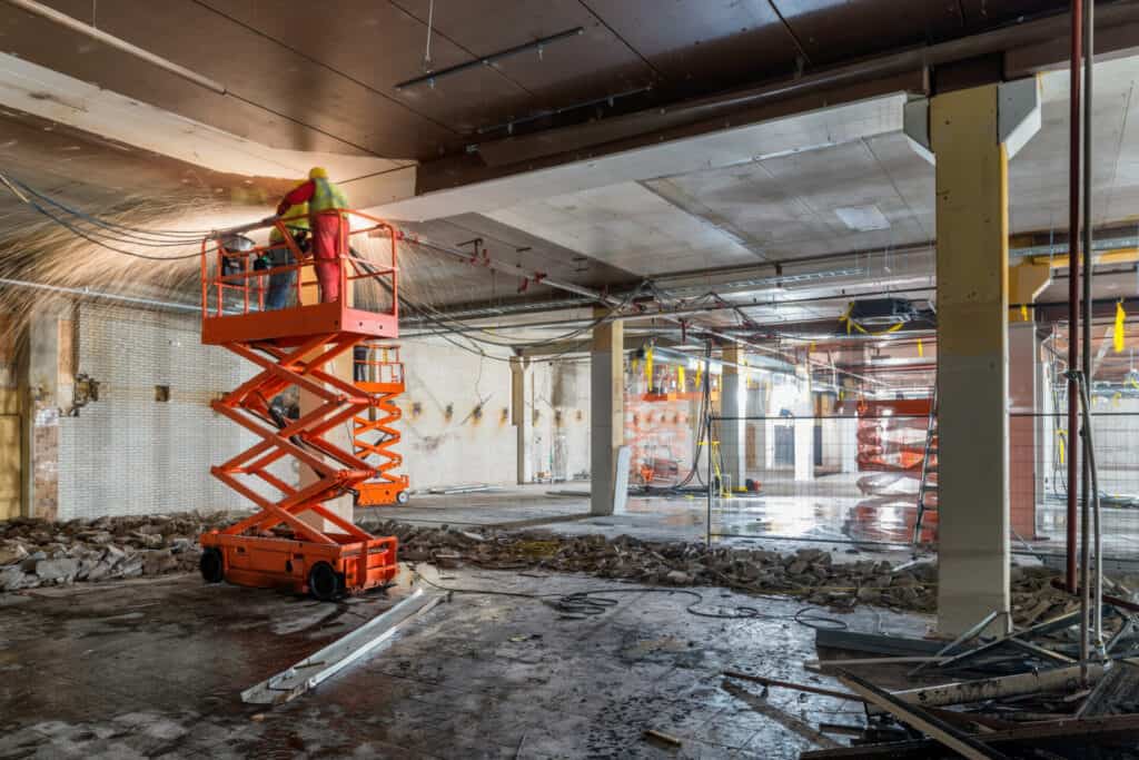 manual workers welding at construction site while standing on sc